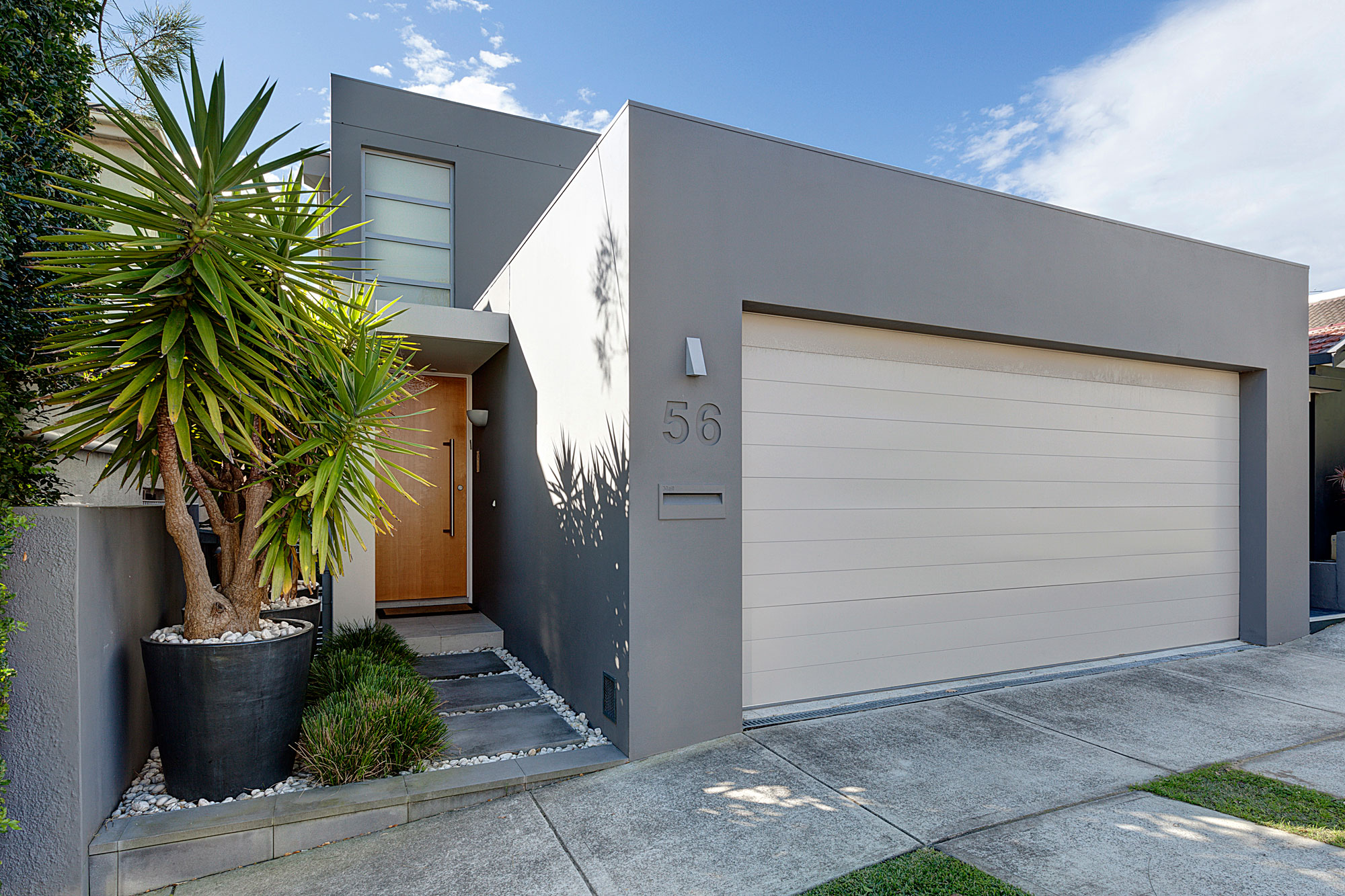 Streetview: modern home in grey rendered exterior and warm wooden front door