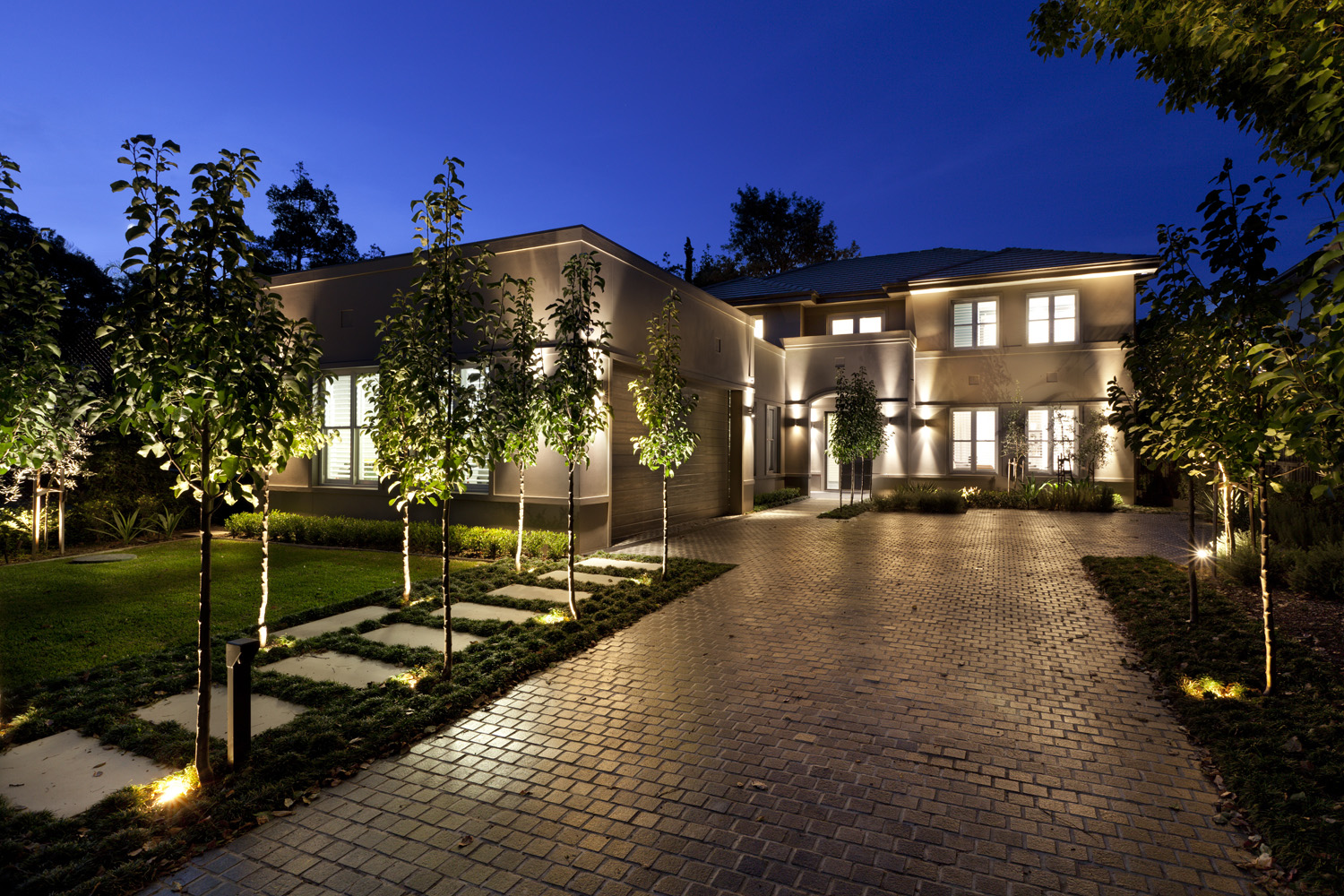 Hunters Hill Modern Traditional: facade and tree-lined entrance lit up in the evening