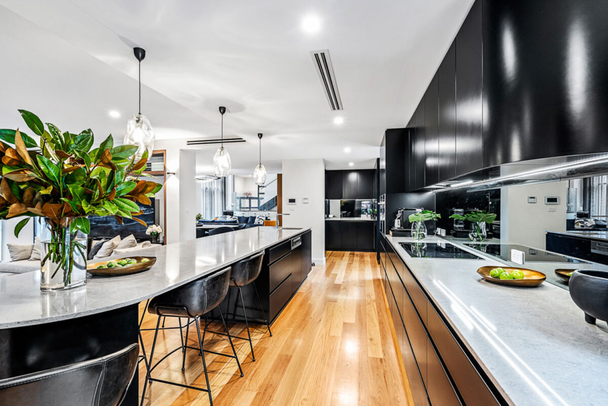 Northbridge Ultra Modern: polished kitchen with curved kitchen bench flowing into dining table