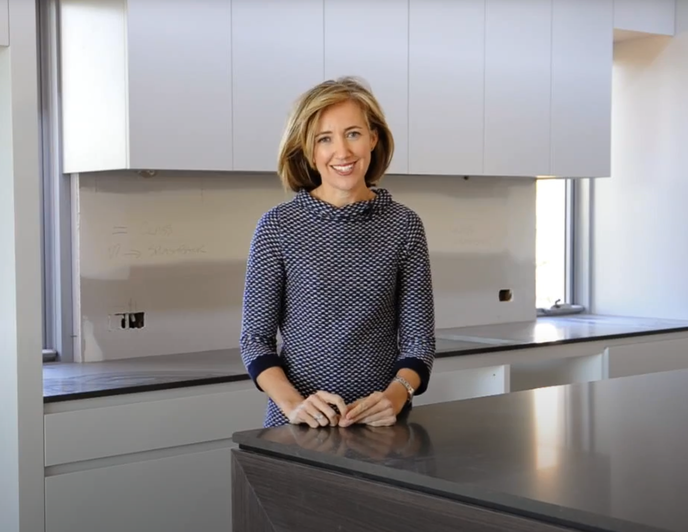 Well presented woman talking to the camera while standing in a kitchen