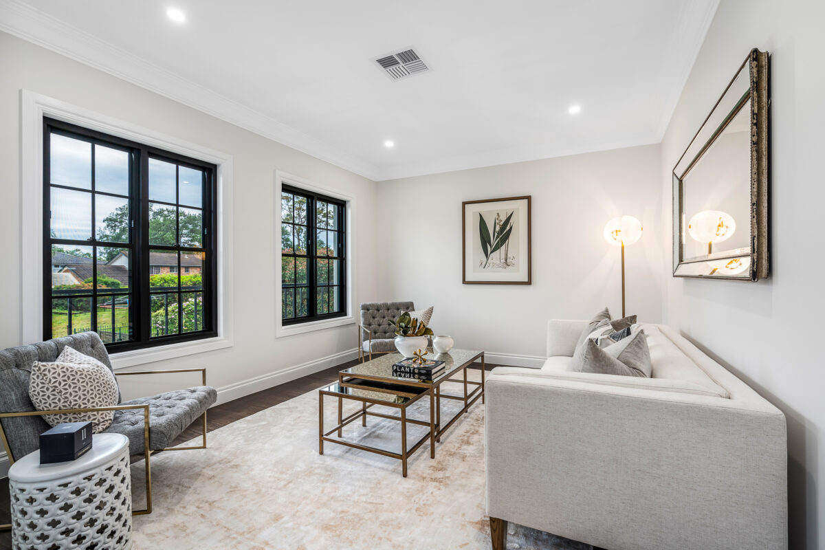 Elegant sitting room with cream sofa, grey armchairs, black-framed windows and gold coffee table