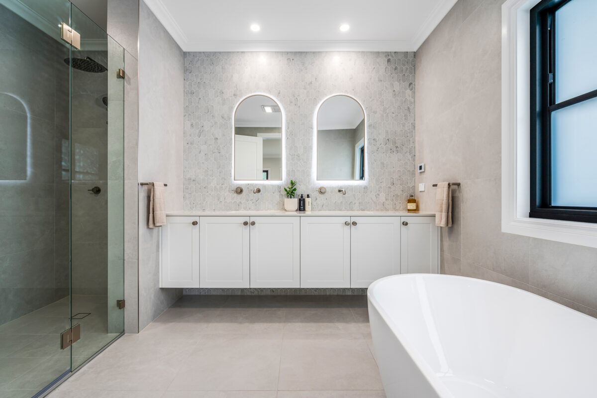 Classical Luxury bathroom with double vanity, arched mirrors, freestanding bath and glass shower