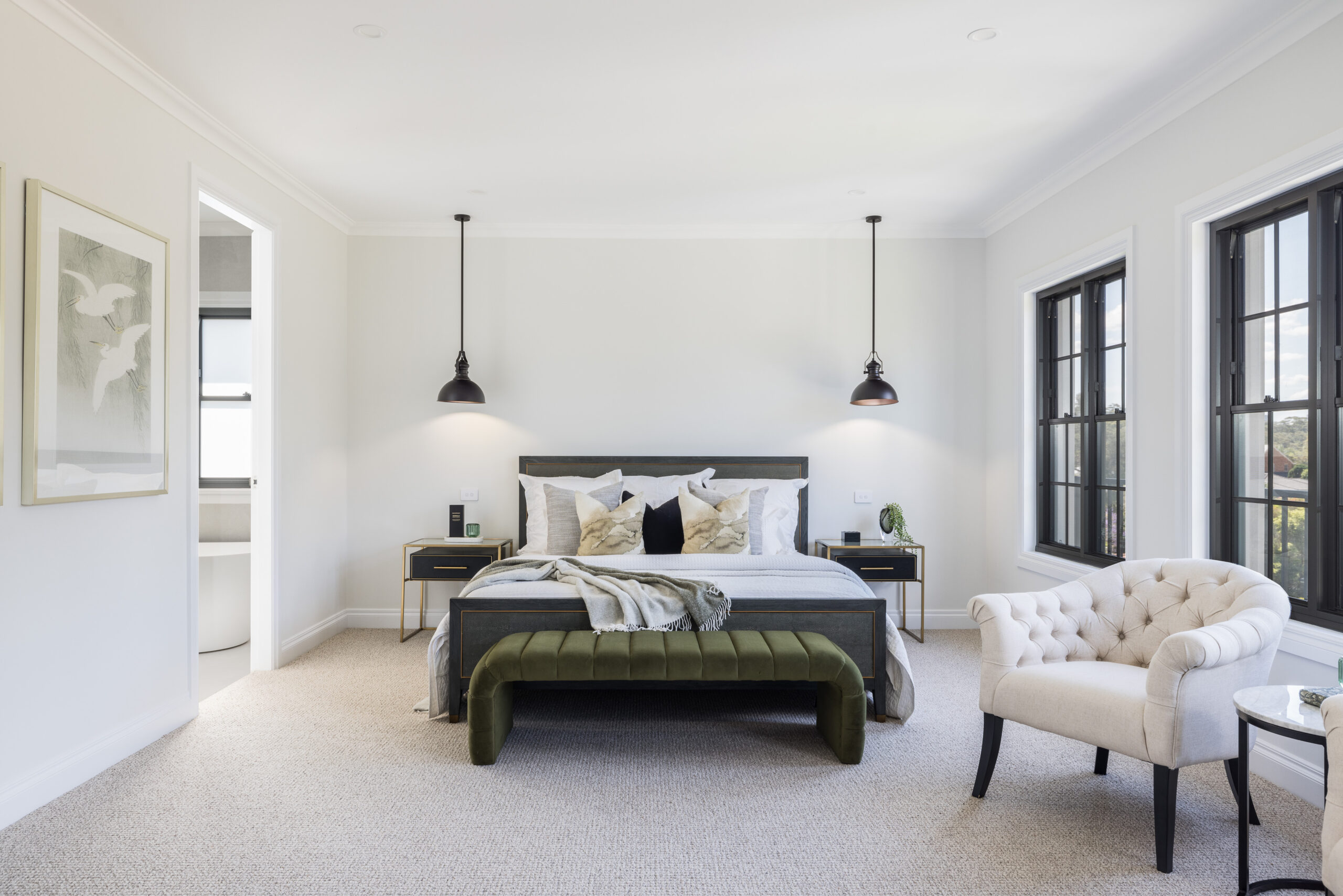 Spacious master bedroom with upholstered bed, pendant lighting, sitting chair and black-framed windows
