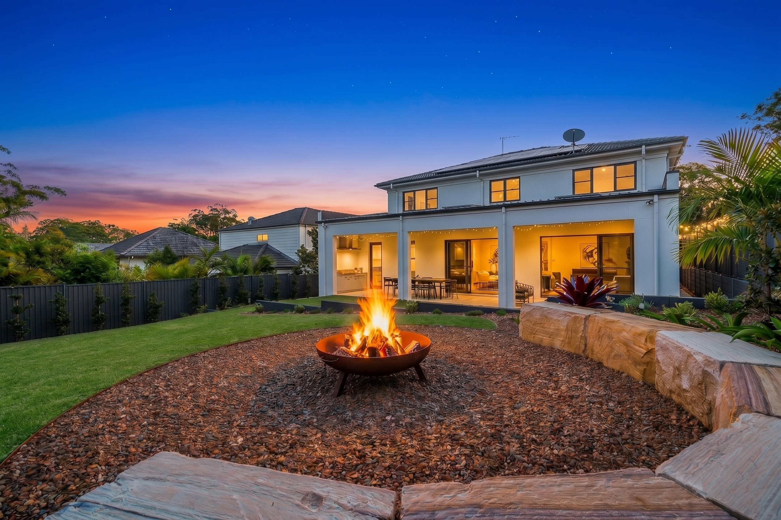 Classical Luxury Family Living with a Landscaped backyard featuring a covered alfresco area, outdoor fire pit, lawn and rear view of the two-storey home