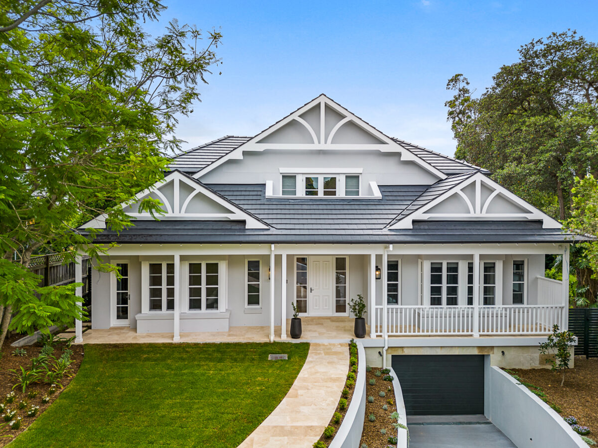 White Contemporary Hamptons custom home with gabled rooflines, front verandah, landscaped garden and basement garage entry.