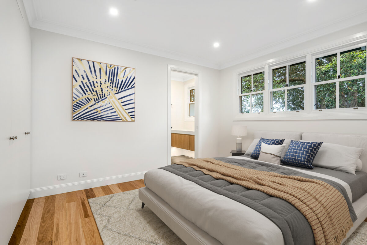 Light-filled sitting room with soft neutral furnishings, timber flooring and expansive windows