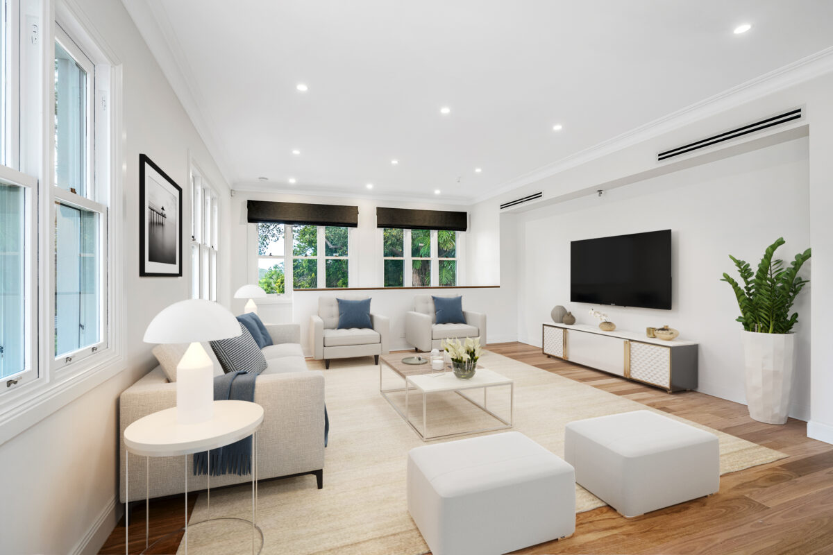 Bright family lounge with neutral furnishings, timber flooring and leafy window views.