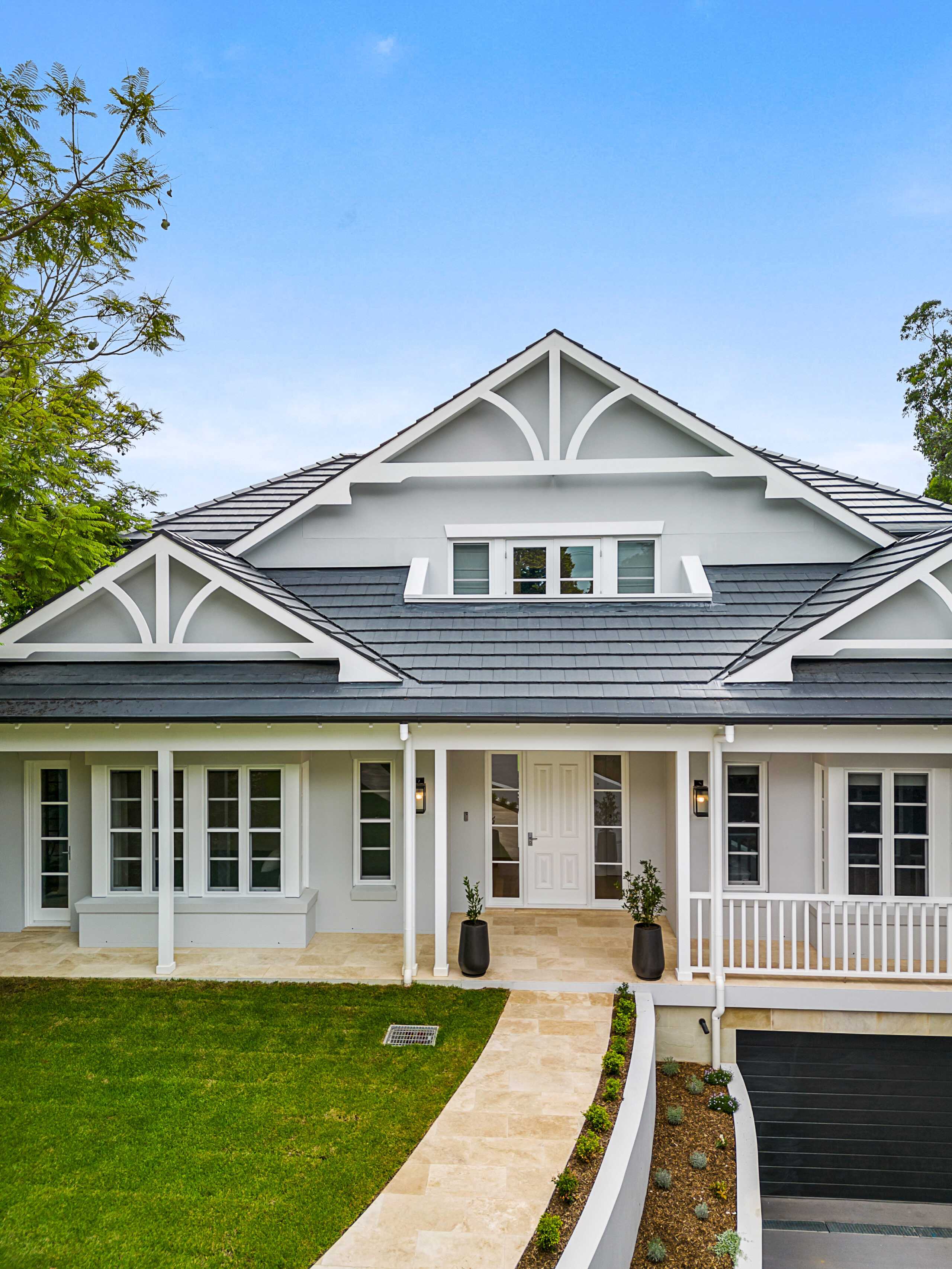 Elegant Contemporary Hamptons façade with layered gables, a verandah and landscaped entry path.